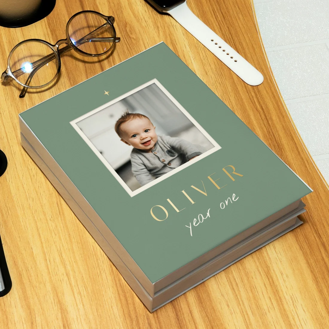 An Oliver, year one book in sage with a framed photo, lying on a wooden desk