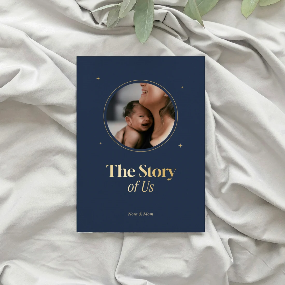 A navy The Story of Us book with a round photo, on white bed sheets