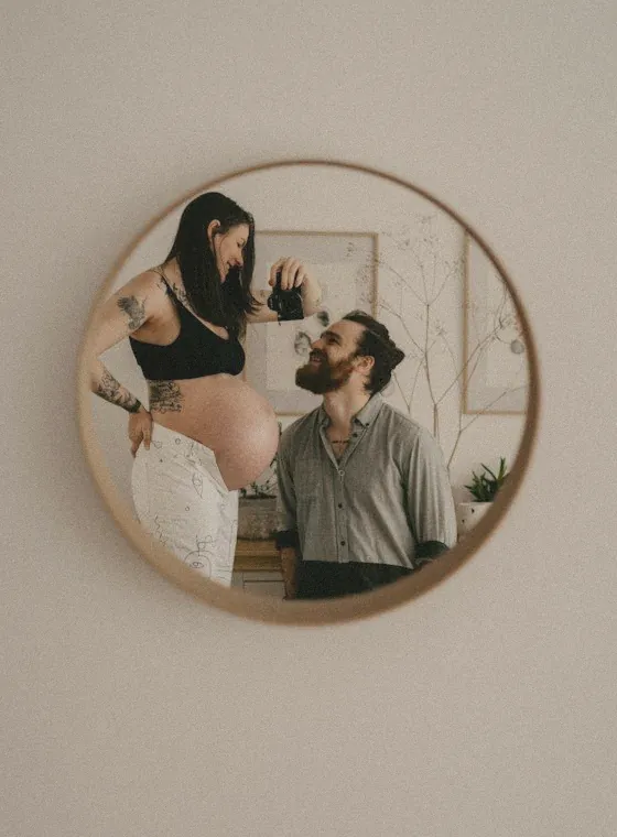 Expecting couple taking a mirror photo at home