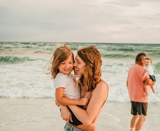 A mom and her toddler laughing at the beach