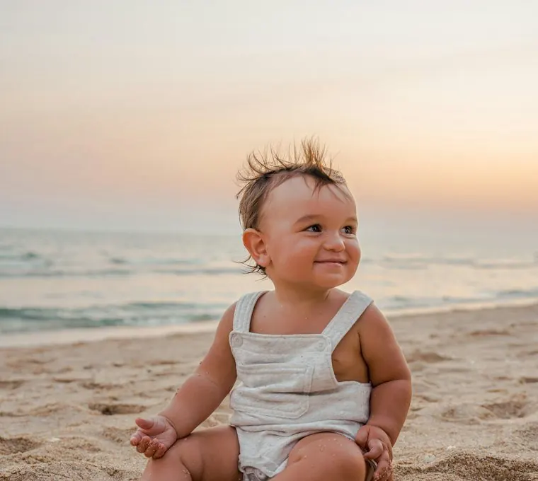 Baby sitting in the sand at the beach